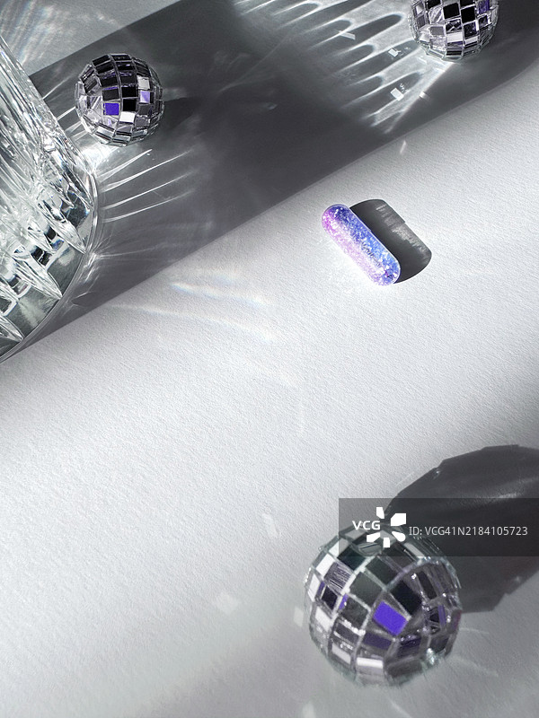 由胶囊制成的闪亮背景，带有蓝紫粉渐变闪光，闪亮的水晶玻璃与水，闪亮的银色迪斯科球在灰银色背景上，伴有优雅的阴影和精致的圣诞灯光。图片素材
