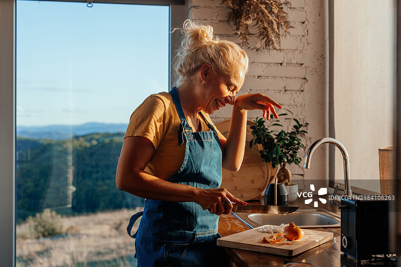 老年女性在厨房切洋葱。图片素材