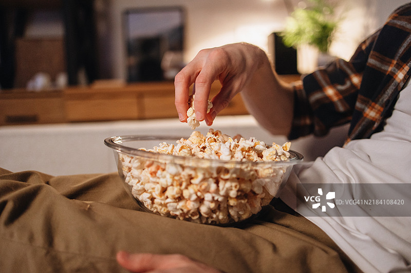 男人的手在家看电影时从碗里抓取爆米花的特写镜头图片素材