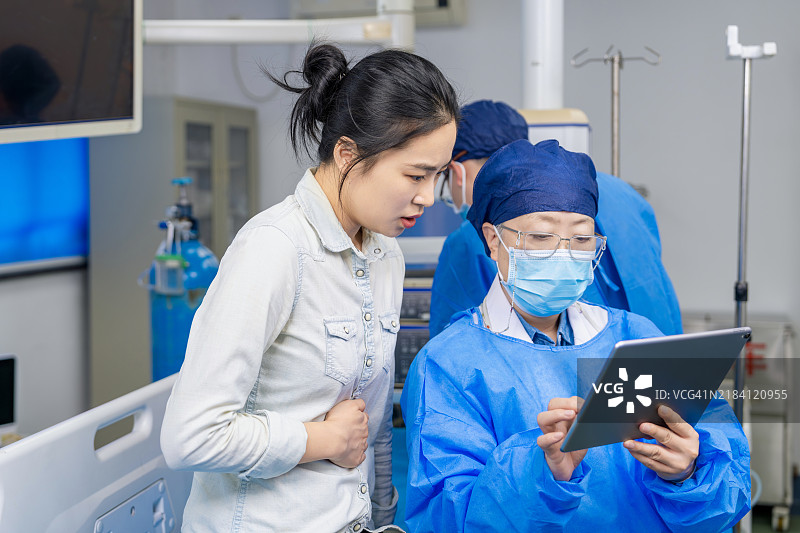 亚洲女性胃肠病学医生在胃镜室使用数字平板与患者沟通治疗方案。图片素材