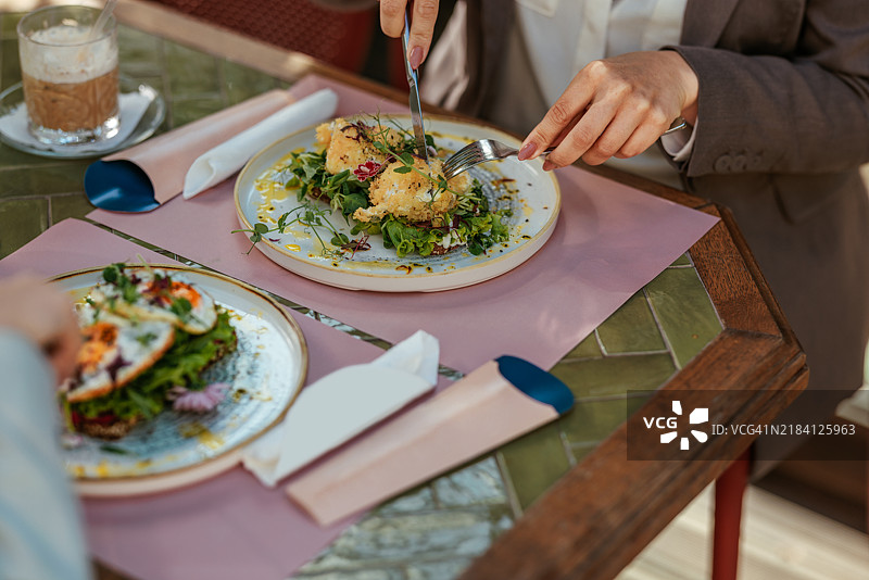 特写镜头：一位女性正在用刀叉切割食物图片素材