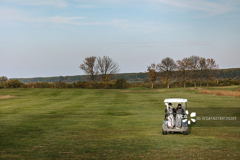 高尔夫球手在球场上享受风景如画的高尔夫球车之旅图片素材