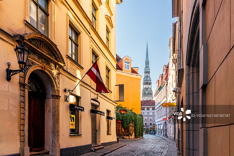 拉脱维亚里加老城的鹅卵石街道和圣彼得教堂在阳光明媚的日子里图片素材