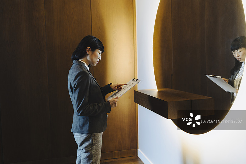 一位女性在家中对着镜子排练演讲。图片素材