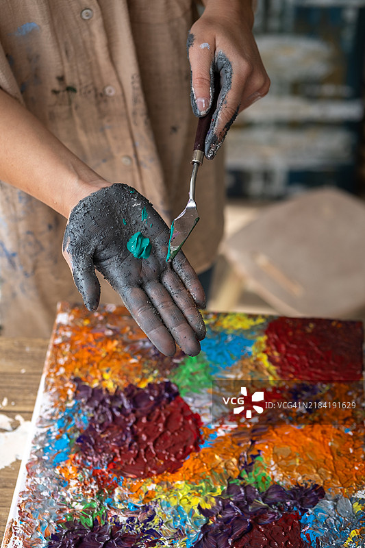 一位艺术家正在调配颜料，以便在手中的画布上作画。图片素材