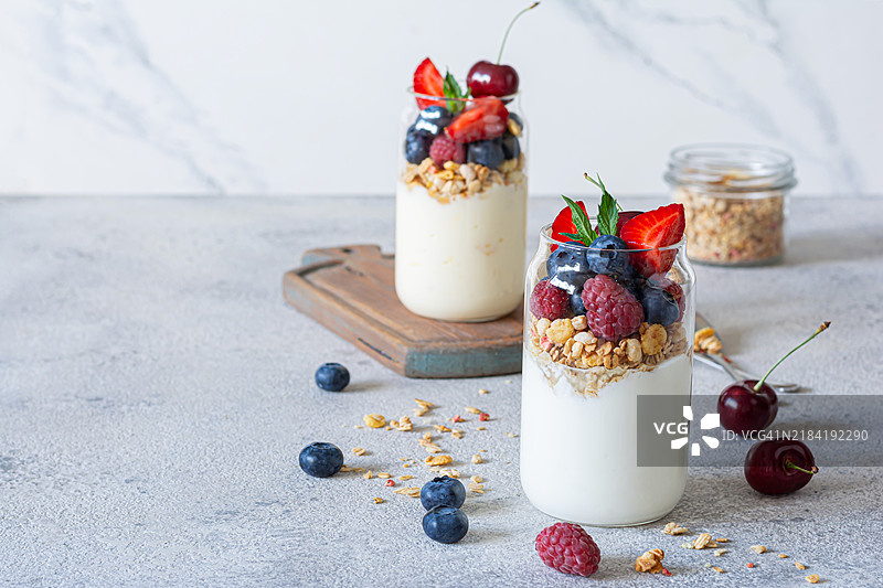 玻璃罐中的酸奶、格兰诺拉麦片和新鲜水果。健康的早餐，零食。外卖概念。图片素材