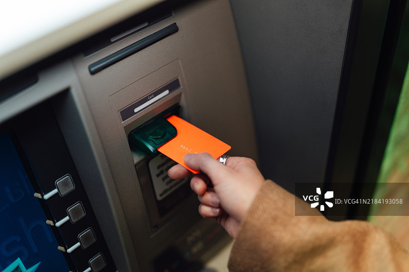 女性手将银行卡插入自动取款机以查询账户余额并提取现金图片素材