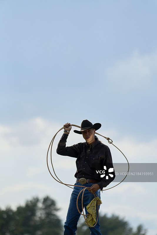 戴着黑色帽子的牛仔在多云的天空背景下握着套索图片素材