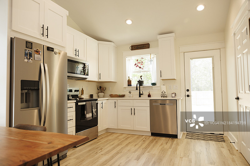 现代厨房内部，配有不锈钢电器、白色橱柜和木质餐桌，佛罗里达州，美国图片素材