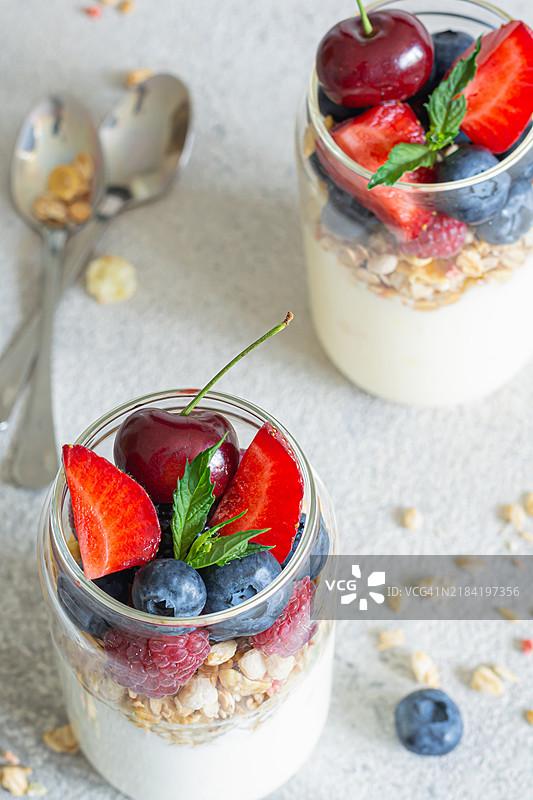 玻璃罐中的酸奶、格兰诺拉麦片和新鲜水果。健康的早餐，零食。外带概念。图片素材