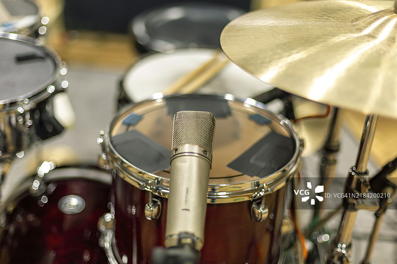 麦克风特写，位于鼓组前面，旁边有一个镲，展示音乐录音或表演的设备设置图片素材