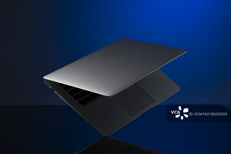 漂浮的银色笔记本电脑，设计简洁，与蓝色渐变背景相映成趣图片素材