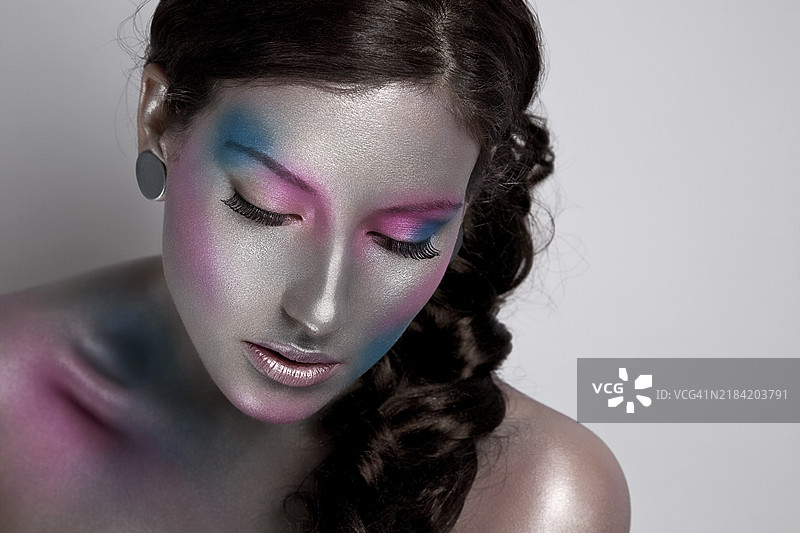 优雅的女性，彩色艺术妆容和编织发型，闭眼摆姿势图片素材