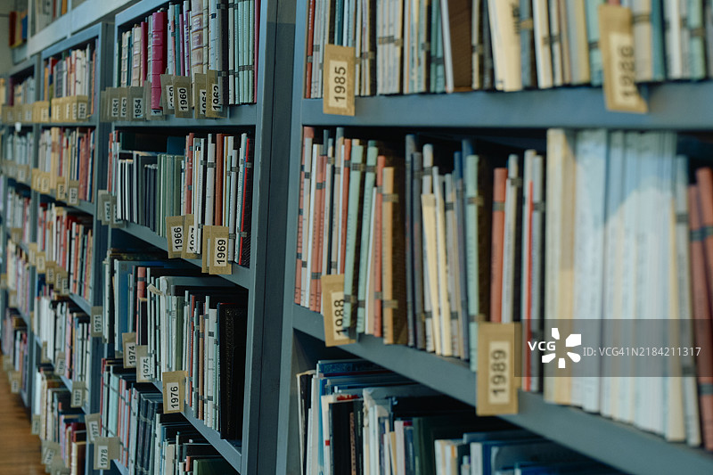 蓝色书架上整齐排列的图书馆书籍，带有数字标签图片素材