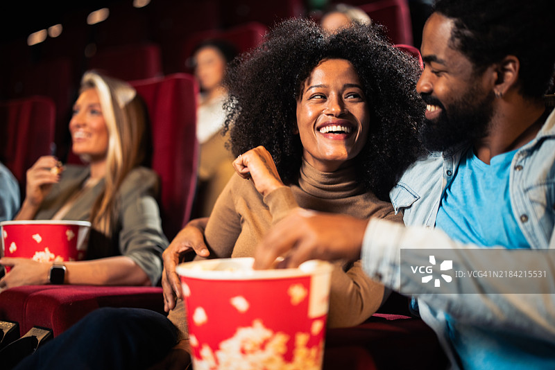情侣在电影院享受乐趣并吃着爆米花图片素材