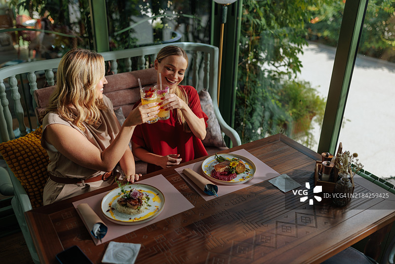 两个女性朋友举杯庆祝，享用鸡尾酒图片素材