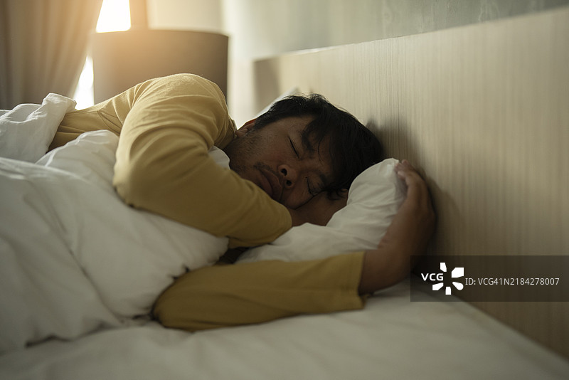 请勿打扰正在床上睡觉的亚洲成年人，手机已关机。图片素材