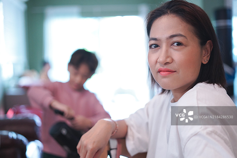 母亲的特写镜头，儿子正在用吸尘器清洁。图片素材