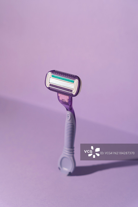 紫色背景下的硬光照射下的塑料剃须刀图片素材