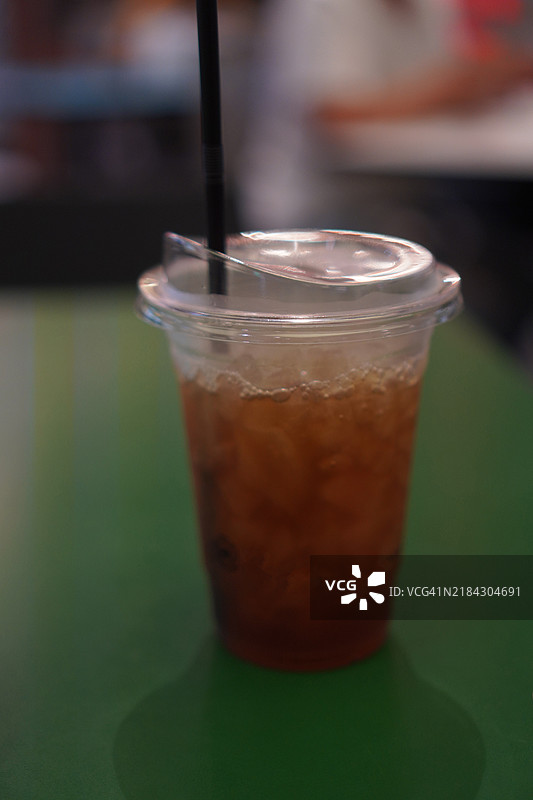 清澈水中的黑冰茶，放在木桌上。饮品图片素材