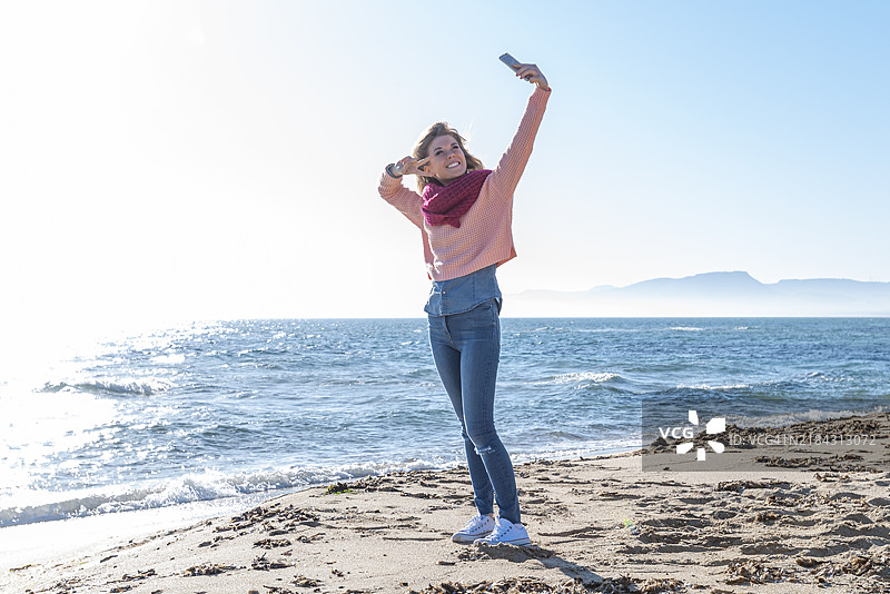 秋天的海滩上，女人在自拍图片素材