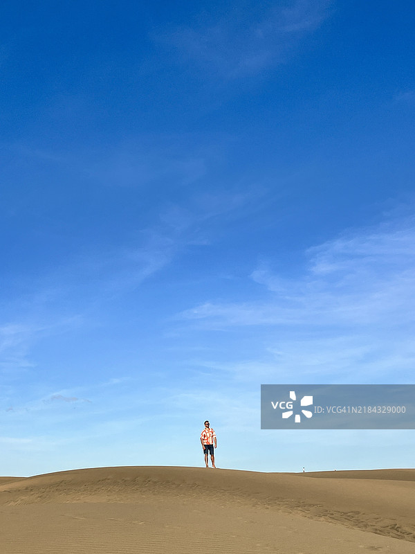 一位年轻的拉丁裔男性背包客在西班牙加那利群岛大加那利岛的马斯帕洛马斯沙漠旅行。图片素材
