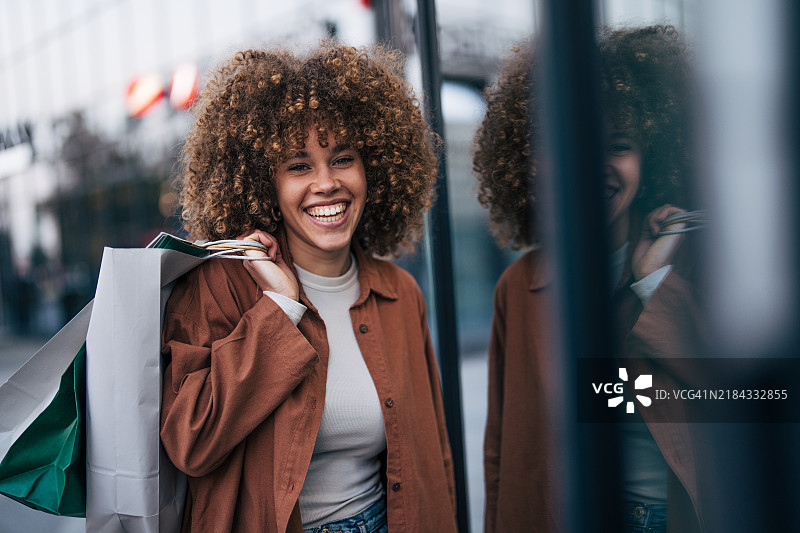 一位23岁的快乐女性在城市街道上享受秋天的日子。图片素材