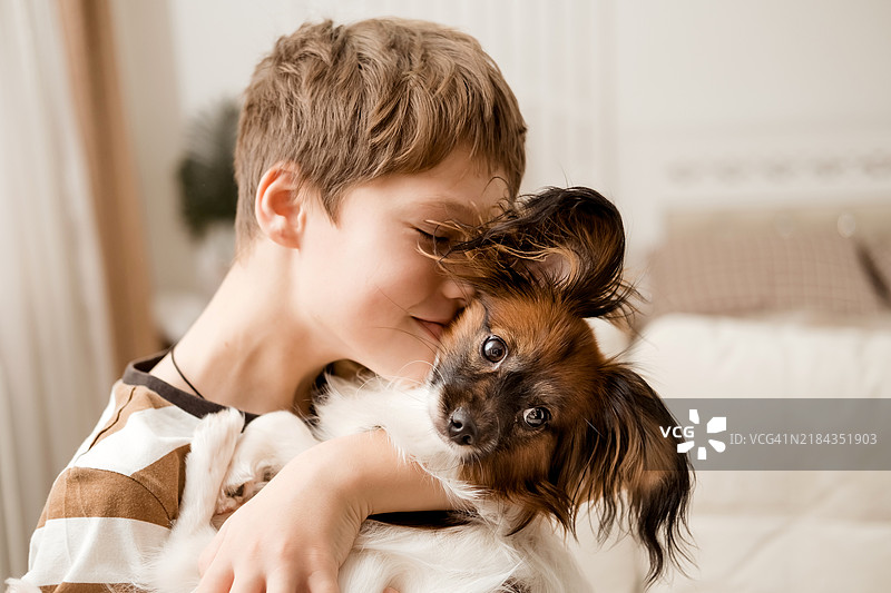 一个快乐的白人男孩拥抱着他的狗。图片素材