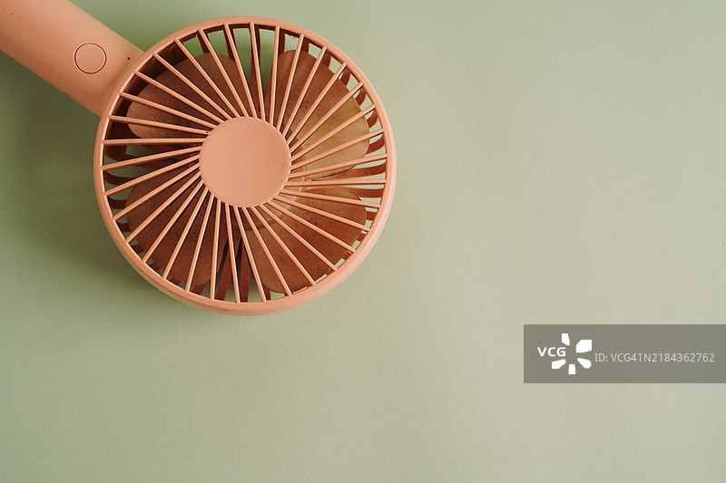 淡绿色背景上的便携式粉色手持风扇图片素材
