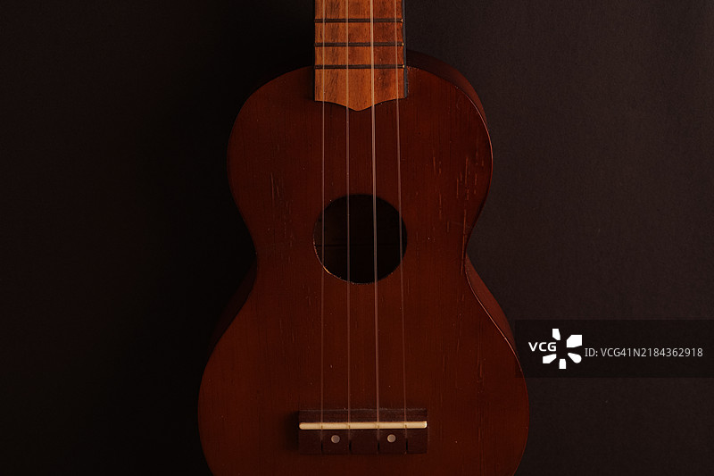 经典木制尤克里里特写在黑色背景上图片素材