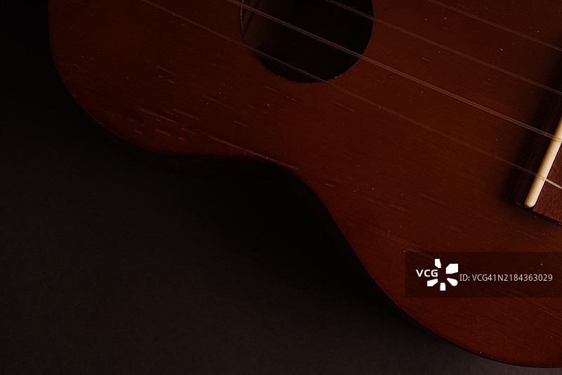 经典木制尤克里里特写在黑色背景上图片素材