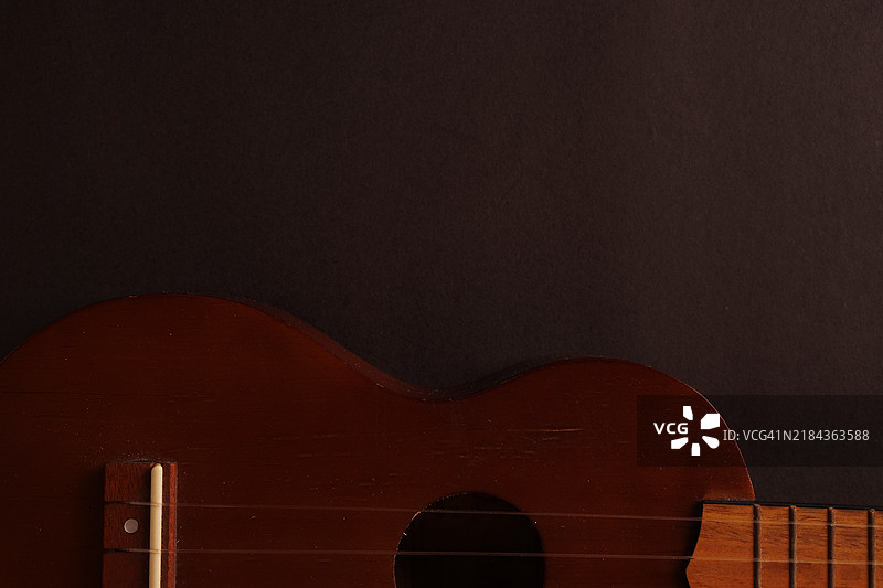 经典木制尤克里里特写在黑色背景上图片素材