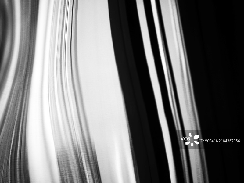 波浪形铝板的特写，上面反射着光线和抽象线条。自然光。单色。法国巴黎。图片素材