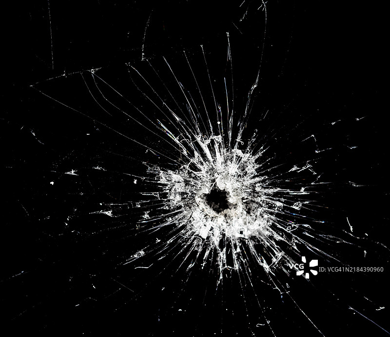 抽象背景，黑色玻璃上有一个子弹孔。图片素材