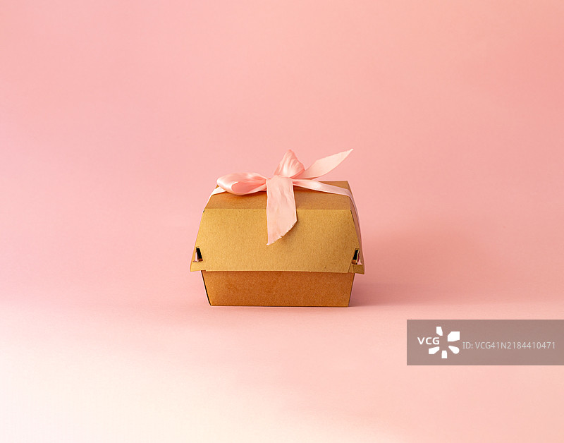 纸板包装，浅粉色背景上的便当蛋糕，浅粉色蝴蝶结图片素材