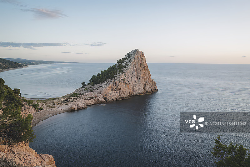 一个难以到达的海角突入海中，背景是弯曲的海岸线图片素材