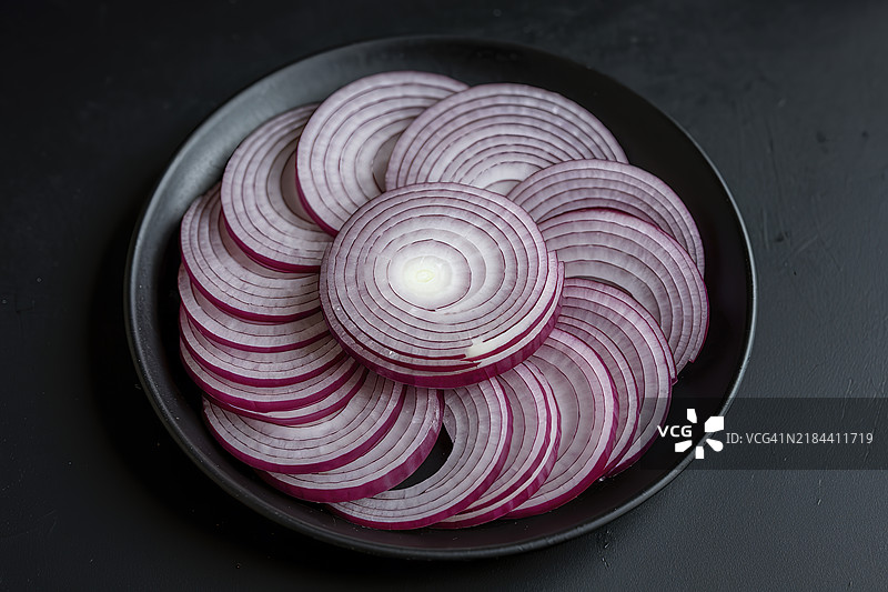 切片的红甜洋葱放在黑色盘子上图片素材