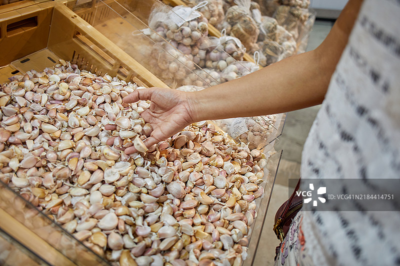 女性在市场上挑选大蒜的中部特写图片素材
