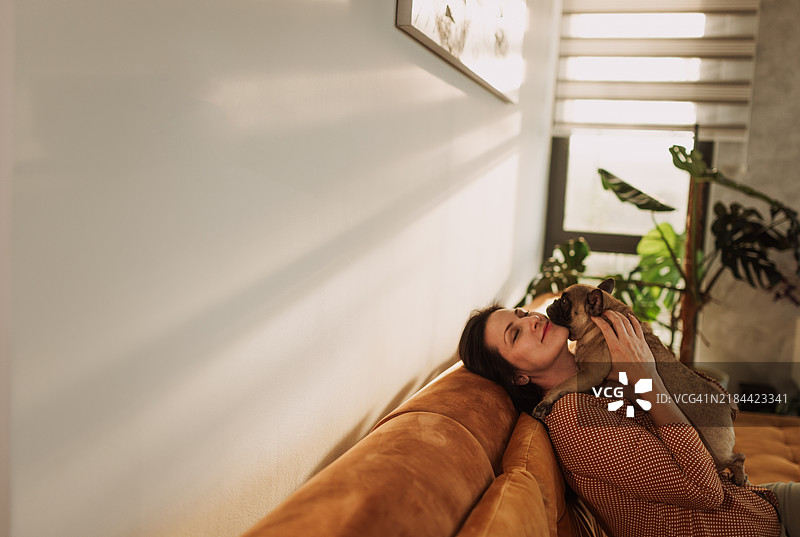 家中女人与她的狗在沙发上享受温馨时刻图片素材