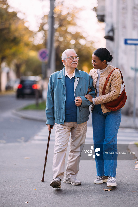 年轻女性陪伴老年人愉快散步图片素材