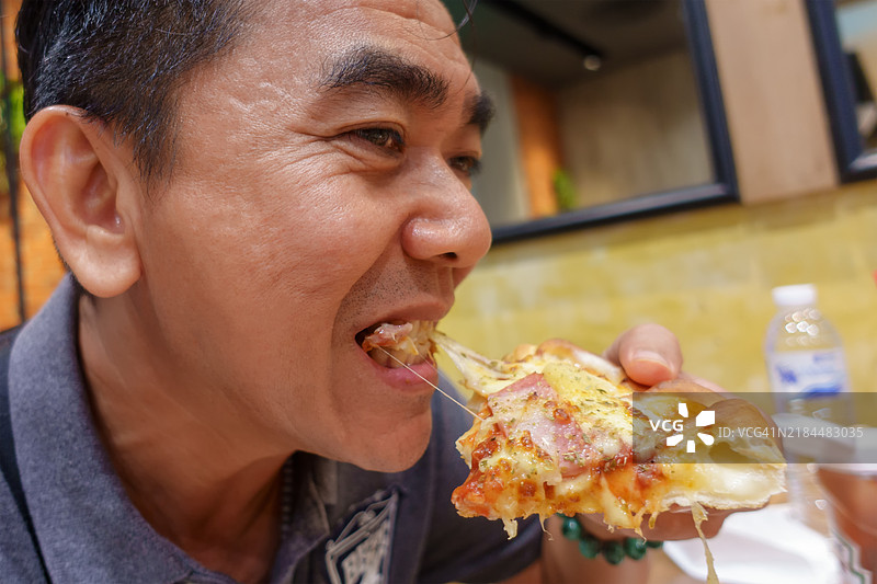 男人愉快地吃着奶酪披萨图片素材