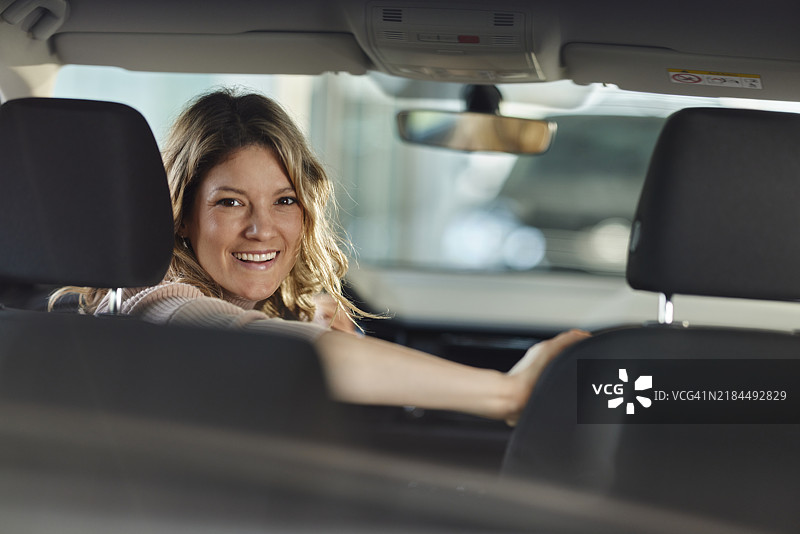 年轻快乐的女性倒车停车。图片素材