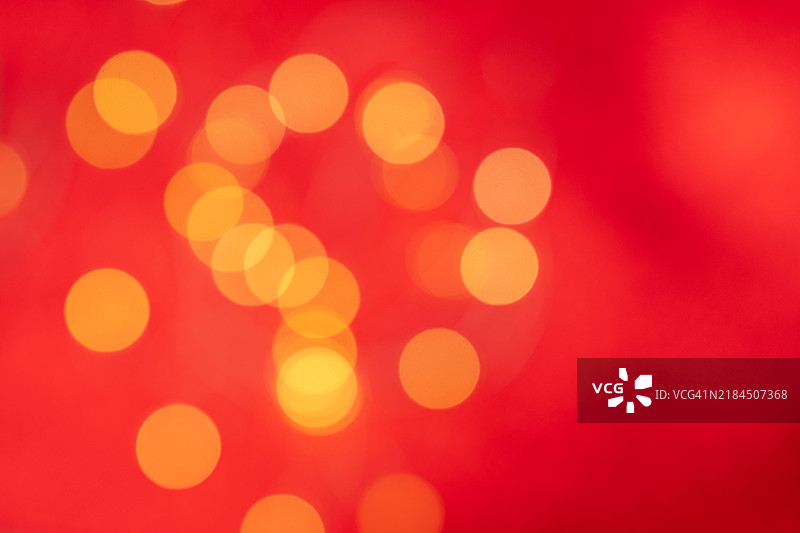 模糊的金色圣诞灯光在红色背景上，完美的节日背景，适合新年或圣诞设计图片素材