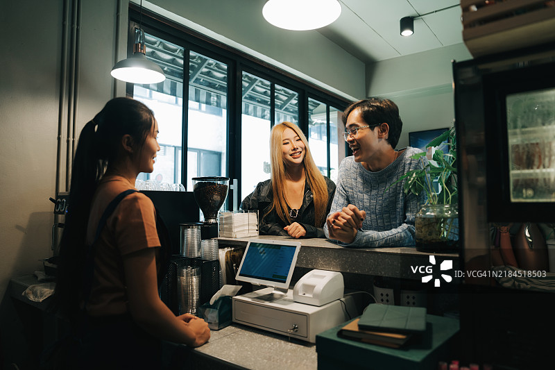 与朋友在时尚环境中点饮料并与咖啡师互动的咖啡时光图片素材
