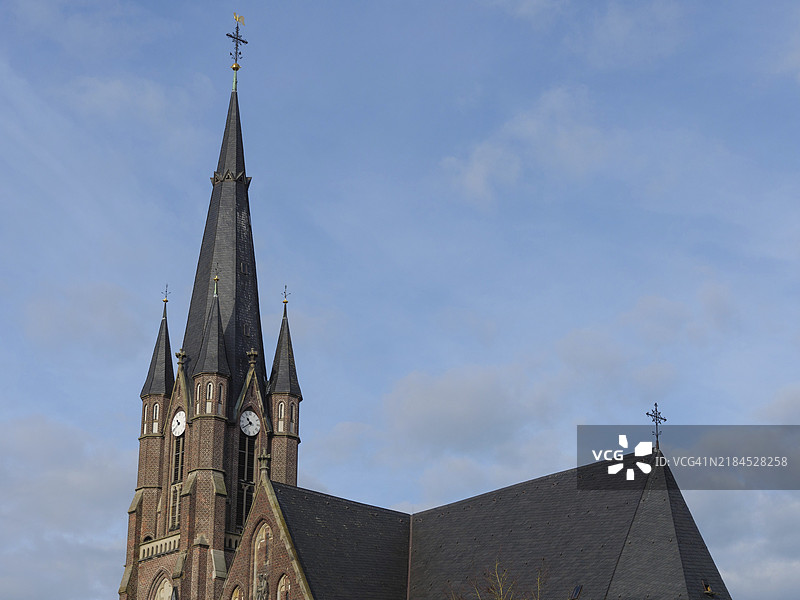 一座尖顶教堂塔楼在蓝天映衬下耸立，位于德国博肯，明斯特地区。图片素材