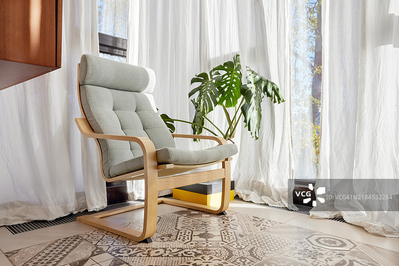 室内轻摇椅，背景是白色窗帘和一株植物，周围无人图片素材
