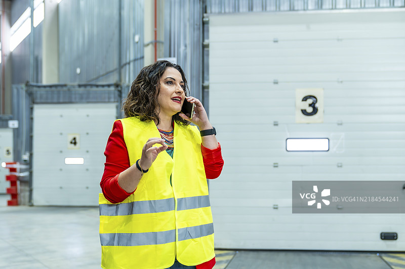 女性在配送仓库工作时与手机通话图片素材