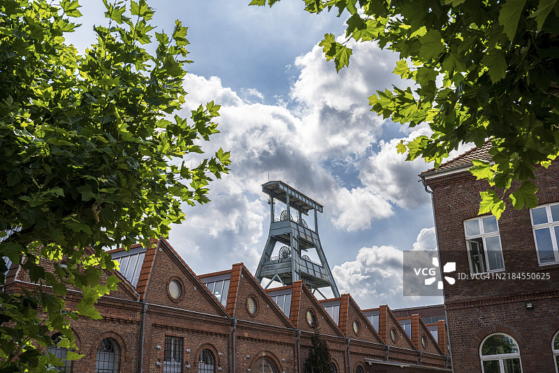 赫尔滕的埃瓦尔德矿井蜿蜒的塔楼，红砖建筑与绿色树木在蓝天的映衬下形成的工业纪念碑。图片素材