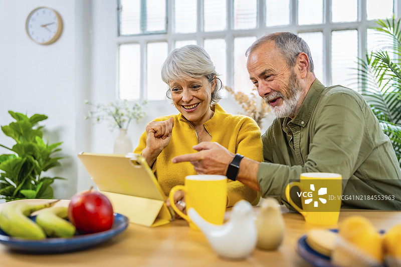 快乐的白人老年夫妇在家使用平板电脑网上购物图片素材