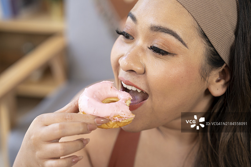 亚洲女性因吃甜甜圈、面包、零食和垃圾食品而增重，这些食物导致肥胖，对人类健康不利。图片素材